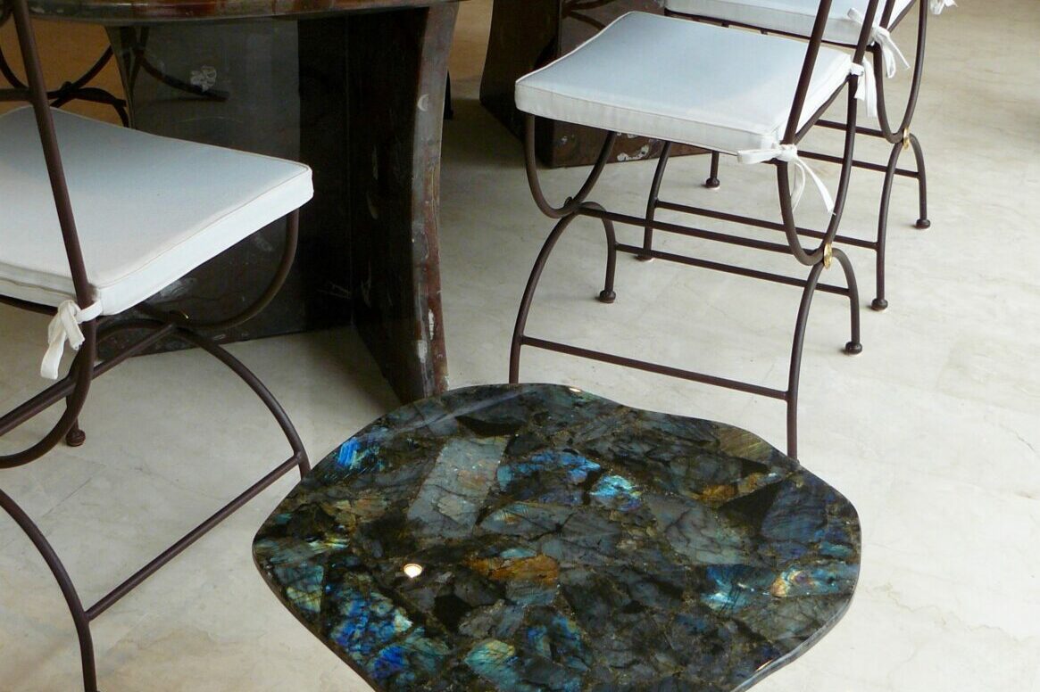 Guéridon en Labradorite et son socle en fer forgé noir. Table de salle à manger en pierre d'Erfoud macrofossiles et ses pieds en pierre