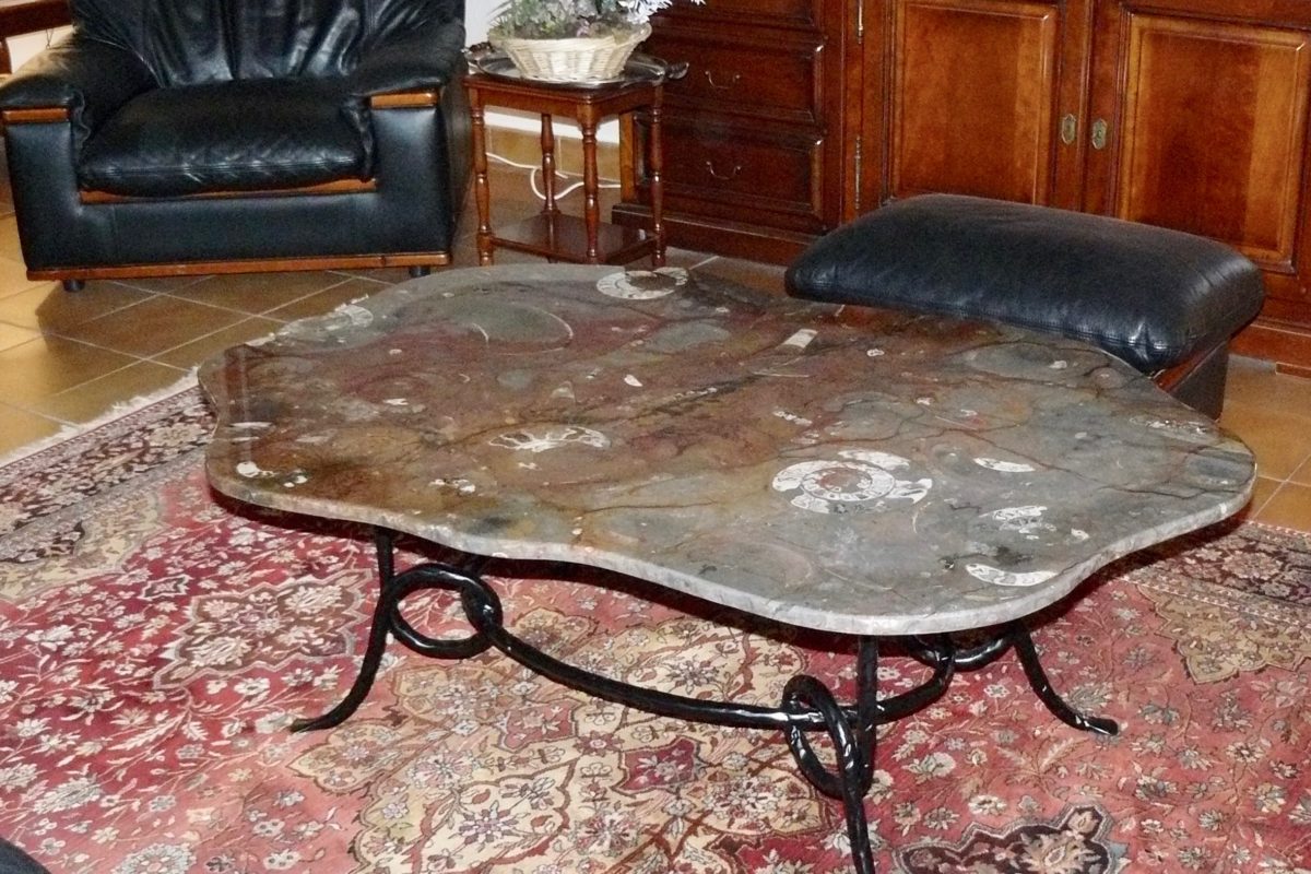 Table irrégulère en pierre d'Erfoud macrofossiles et son socle en fer forgé ovale