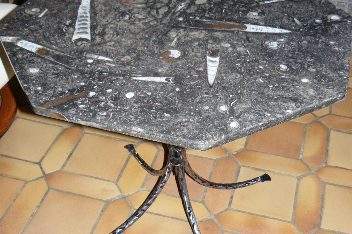 Table octogonale en pierre d'Erfoud en son socle en fer forgé martelé brossé